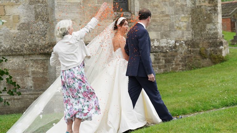 A woman throws orange confetti over former chancellor George Osborne and his wife and former adviser, Thea Rogers