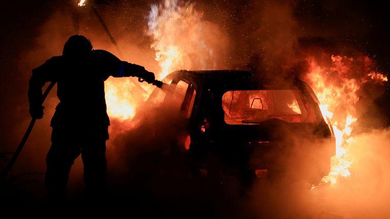 A French firefighter extinguishing a burning car during the fifth night of protests