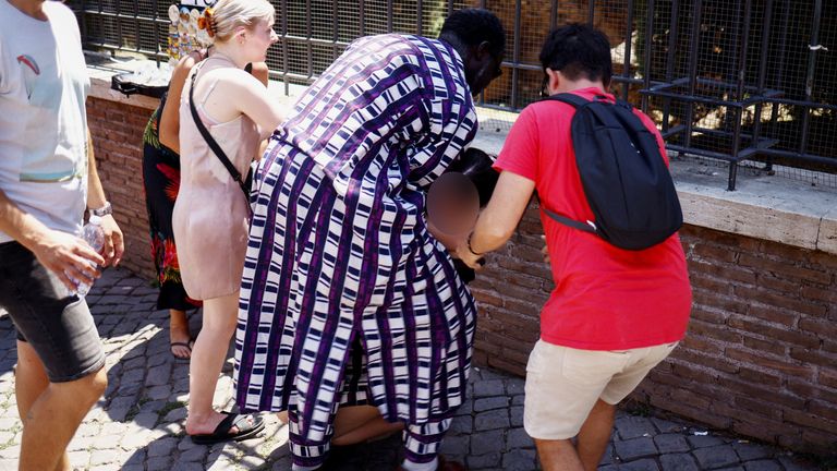 A tourist from the UK receives help near the Colosseum after fainting during a heatwave across Italy 