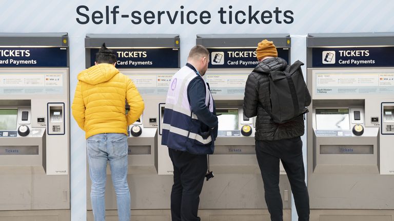 A member of staff assists a person at the ticket machines in Waterloo Station train station in London