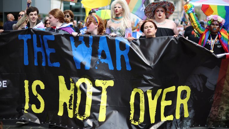 People walk behind an anti-war banner as they take part in the Pride march in Liverpool
