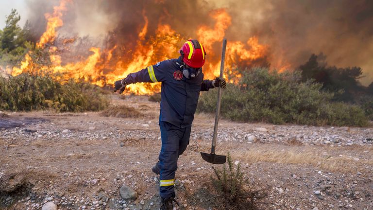 A firefighter leaves as the flames approaching him during a wildfire in Vati village, on the Aegean Sea island of Rhodes Pic:AP