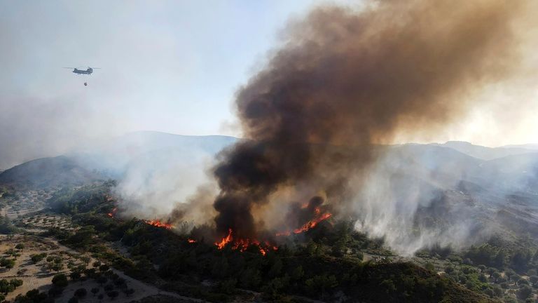 A military helicopter operates as flames burn a forest on the mountains near Vati village, on the Aegean Sea island of Rhodes, southeastern Greece, on Tuesday, July 25, 2023. A third successive heat wave in Greece pushed temperatures back above 40 degrees Celsius (104 degrees Fahrenheit) across parts of the country Tuesday following more nighttime evacuations from fires that have raged out of control for days. (AP Photo/Spiros Tsampikakis)