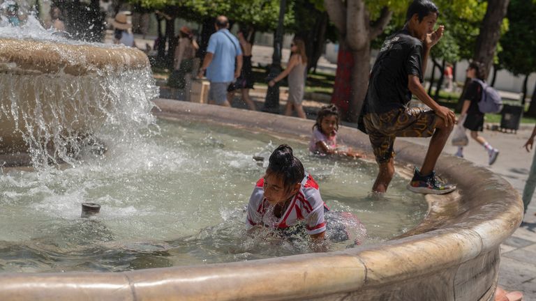 Children cool themselves in a fountain of the central Syntagma square