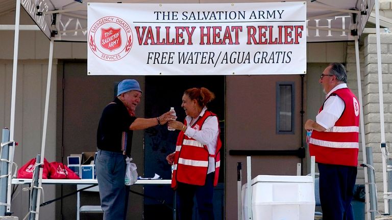 Salvation Army volunteer Francisca Corral, center, gives water to a man at a their Valley Heat Relief Station, Tuesday, July 11, 2023 in Phoenix. (AP Photo/Matt York)