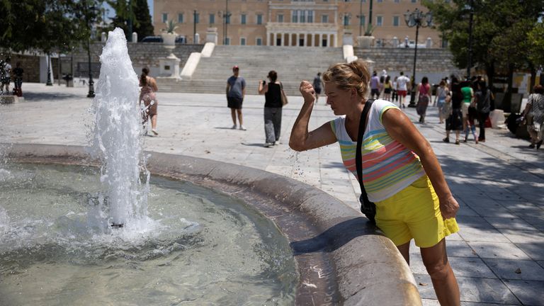 A woman cools down on Syntagma Square, in front of the parliament building, during a heatwave in Athens, Greece, July 13, 2023. REUTERS/Stelios Misinas