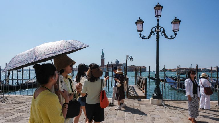 Tourists shelter from the sun with umbrellas in St. Mark's Square as the city gears up for 'Redentore' festival celebrations in Venice, Italy, July 15, 2023. REUTERS/Manuel Silvestri