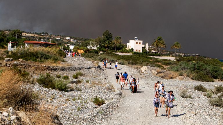 Tourists are being evacuated as wildfire burns near Lindos, on the island of Rhodes, Greecce