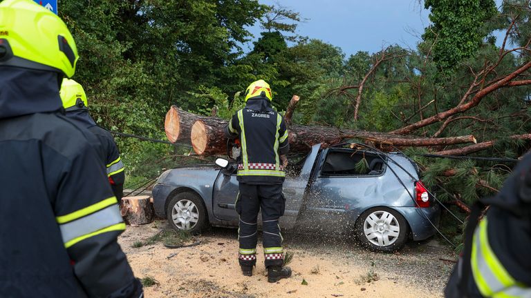 İtfaiyeciler, 19 Temmuz 2023 Çarşamba günü Hırvatistan'ın Zagreb kentinde şiddetli bir fırtınanın ardından park halindeki hasarlı arabadan düşen ağaç dallarını çıkarıyor. Çarşamba günü şiddetli rüzgarlar ve şiddetli yağmurla birlikte güçlü bir fırtına Hırvatistan ve Slovenya'yı vurarak en az üç kişinin ölümüne ve çok sayıda kişinin yaralanmasına yol açtı. diğerleri.  (AP Fotoğrafı)