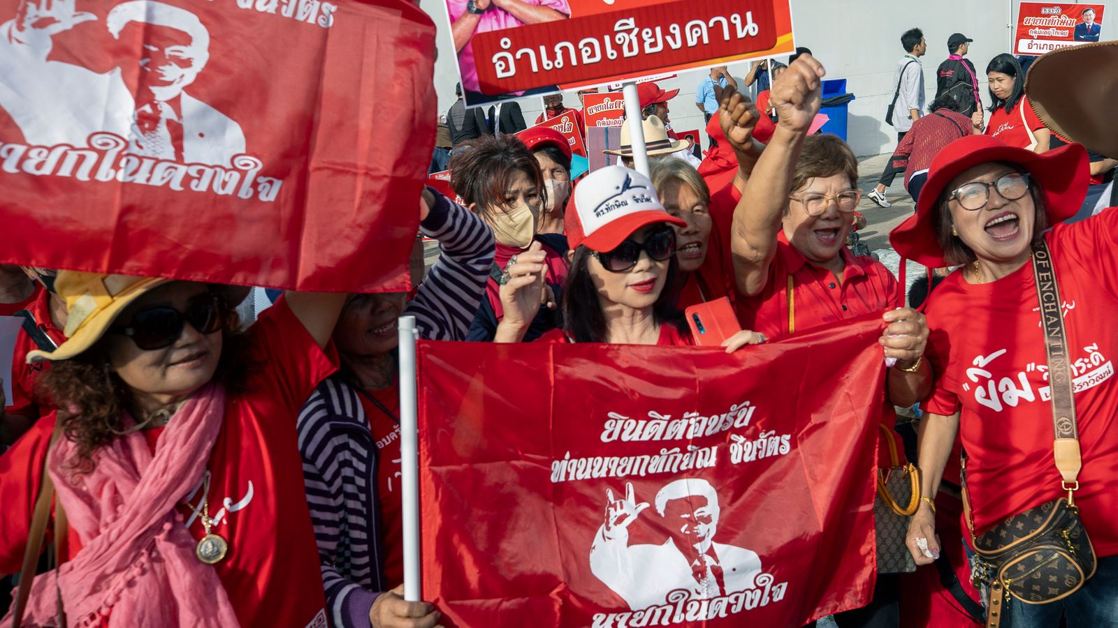 Поддръжници, чакащи развълнувани зад оградите, аплодираха ние обичаме Таксин“.Изображение: Бившият