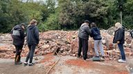 People inspect the rubble remains as they gather at The Crooked House