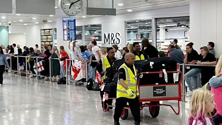Airport staff with luggage pass through arrivals as England fans await the arrival of the England Women&#39;s team at London Heathrow Airport. Sarina Wiegman...s side lost 1-0 to Spain in a tight match in Sydney on Sunday. Picture date: Tuesday August 22, 2023. PA Photo. See PA story SOCCER England. Photo credit should read: Andrew Matthews/PA Wire...RESTRICTIONS: Use subject to restrictions. Editorial use only, no commercial use without prior consent from rights holder.
