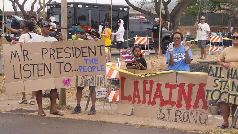 People hold up signs as U.S. President Joe Biden and First Lady Jill Biden visit the fire-ravaged town of Lahaina on the island of Maui in Hawaii, U.S. August 21, 2023. REUTERS/Kevin Lamarque