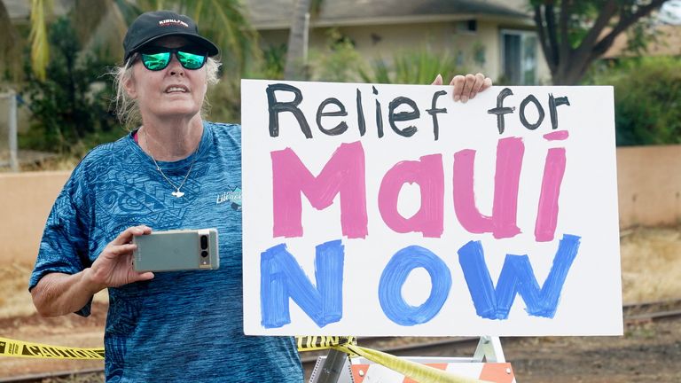 A woman holds a sign as U.S. President Joe Biden and first lady Jill Biden visit the fire-ravaged town of Lahaina on the island of Maui in Hawaii, U.S., August 21, 2023. REUTERS/Kevin Lamarque
