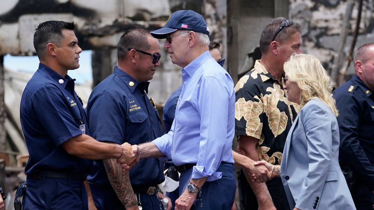 President Joe Biden and first lady Jill Biden greet first responders as they tour areas devastated by the Maui wildfires, Monday, Aug. 21, 2023, in Lahaina, Hawaii. In the background is the massive Banyan Tree burned in the fire. (AP Photo/Evan Vucci)