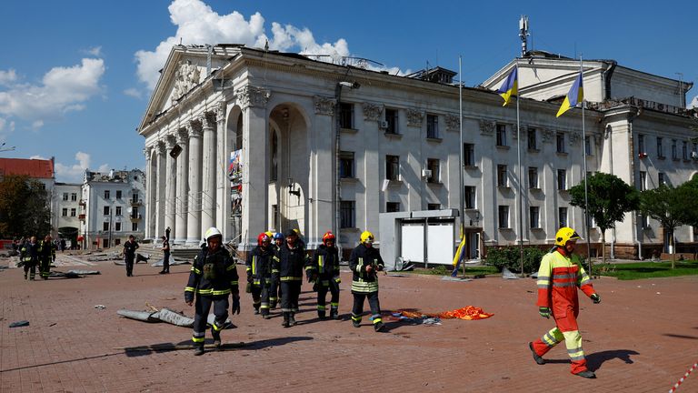 Rescue workers walk past the city&#39;s theatre after the missile strike