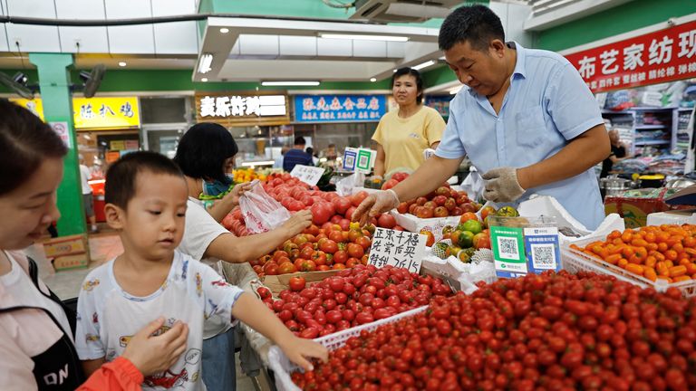 Customers select tomatoes at a stall inside a morning market in Beijing, China August 9, 2023. REUTERS/Tingshu Wang