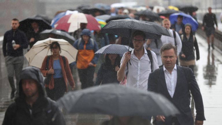 Commuters carry umbrellas while crossing London Bridge in London, Britain August 2, 2023. REUTERS/Hollie Adams..