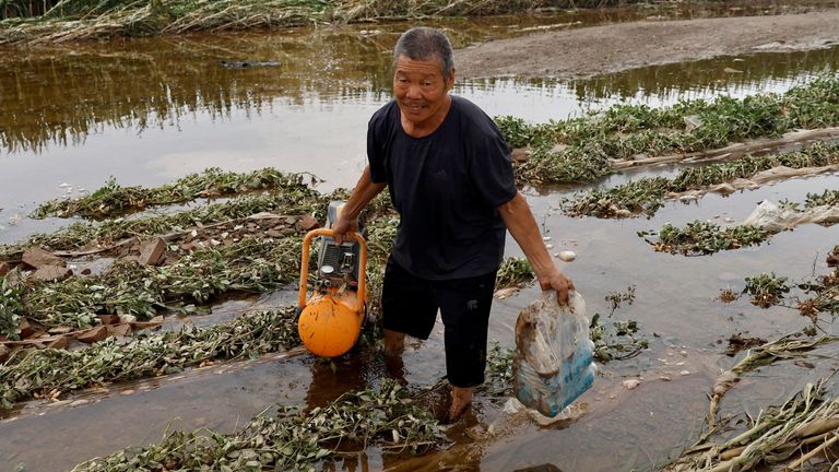 FILE PHOTO: A man wades through floodwaters in a flooded corn farm after the rains and floods brought by remnants of Typhoon Doksuri, in Zhuozhou, Hebei province, China August 7, 2023. REUTERS/Tingshu Wang/File Photo
