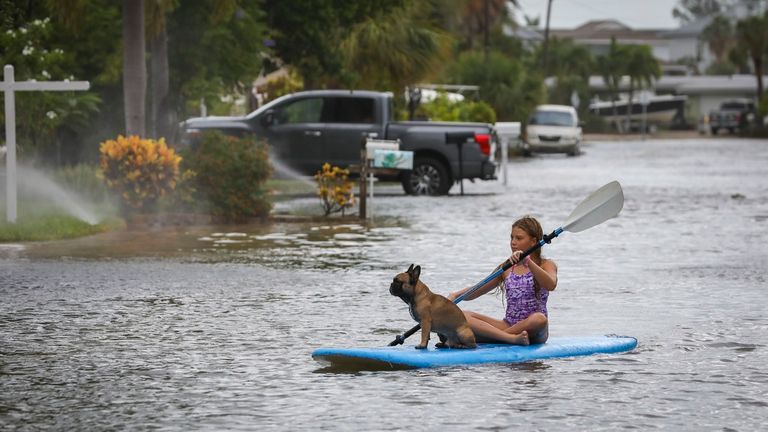 A woman and her dog paddle through waters in St. Pete Beach, Florida. Pic: AP