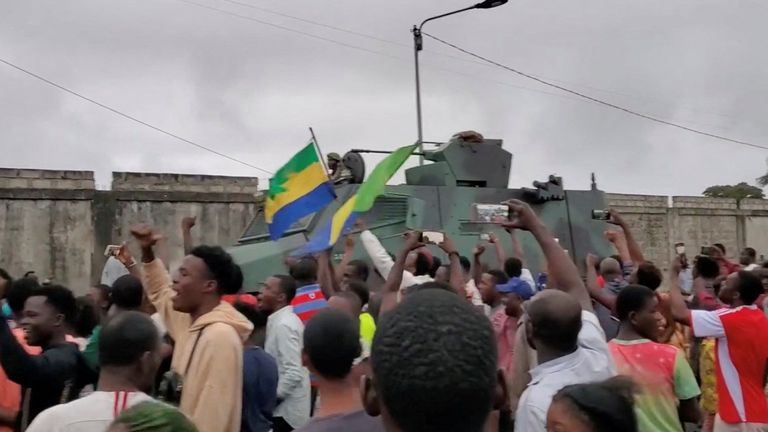A military vehicle passes people celebrating in Port Gentil after soldiers announced a coup. Pic: Gaetan M-Antchouwet/Reuters