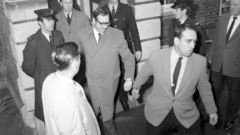 Bruce Reynolds, wearing glasses, leaves a five-minute court appearance in 1968