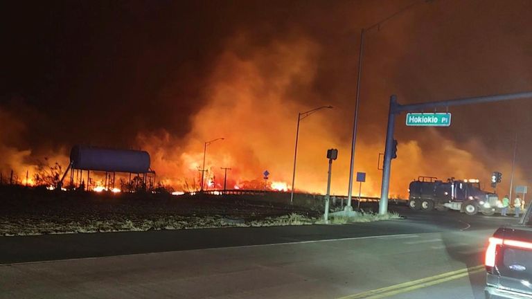 This photo provided by County of Maui shows fire and smoke filling the sky from wildfires on the intersection at Hokiokio Place and Lahaina Bypass in Maui, Hawaii on Tuesday, Aug. 8, 2023.   Wildfires in Hawaii fanned by strong winds burned multiple structures in areas including historic Lahaina town, forcing evacuations and closing schools in several communities Wednesday, and rescuers pulled a dozen people escaping smoke and flames from the ocean. (Zeke Kalua/County of Maui via AP)