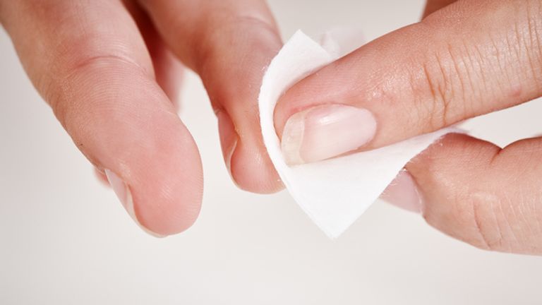 An unrecognizable person&#39;s hands use a sterile wipe  to clean hands before suing a lancet to do a fingerprick blood test.