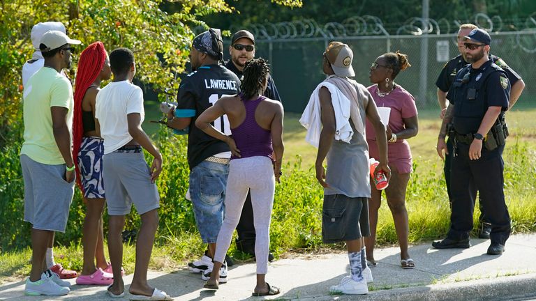 Residents talk with Jacksonville police officers near the scene of a mass shooting at a Dollar General store, Saturday, Aug. 26, 2023, in Jacksonville, Fla. (AP Photo/John Raoux)