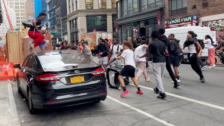 A man jumps on a car as a crowd runs through the street on Broadway near Union Square. Pic: AP