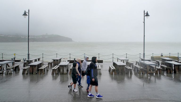 A family walks amongst empty picnic tables during bad weather in Folkestone, Kent. Picture date: Monday July 31, 2023.


