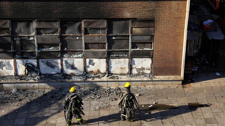 Firefighters walk at the scene of a deadly blaze, in Johannesburg, South Africa  