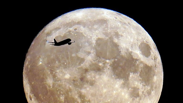 A plane passes the super blue moon in London