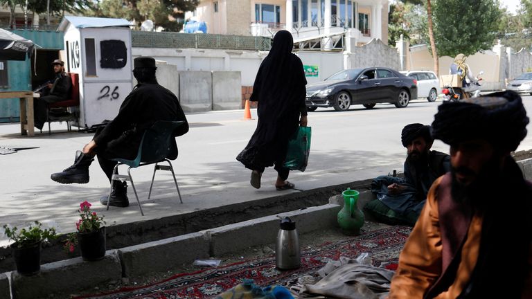 An Afghan woman walks among Taliban soldiers at a checkpoint in Kabul, Afghanistan, July 6, 2023. REUTERS/Ali Khara