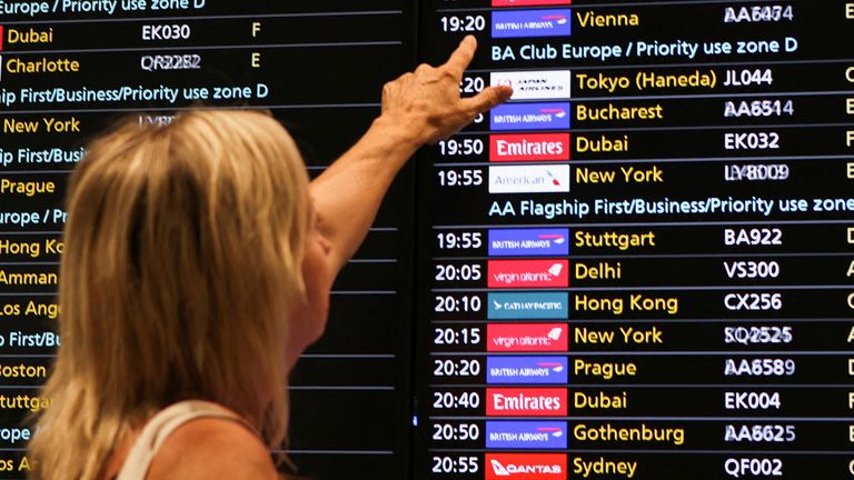 A woman points at a flight board at Heathrow Airport, as Britain&#39;s National Air Traffic Service (NATS) restricts UK air traffic due to a technical issue causing delays