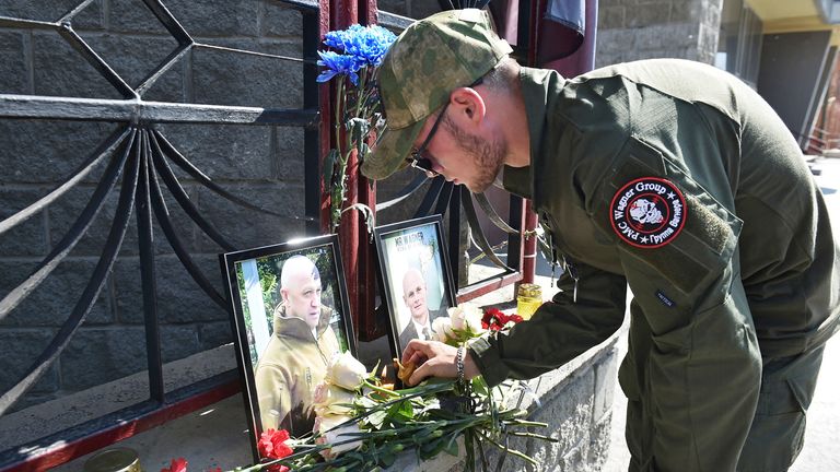 A fighter of Wagner private mercenary group lights a candle at a makeshift memorial with portraits of Russian mercenary chief Yevgeny Prigozhin and Wagner group commander Dmitry Utkin outside the local office of the Wagner private mercenary group in Novosibirsk, Russia August 24, 2023. REUTERS/Stringer