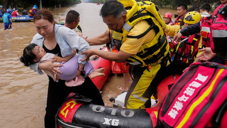 A rescuer helps a woman with a child disembark from a rubber boat as trapped residents evacuate through floodwaters in Zhuozhou in northern China&#39;s Hebei province, south of Beijing
Pic:AP