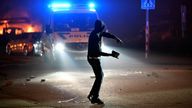 A person prepares to throw a stone as cars burn during a riot in Malmo, Sweden