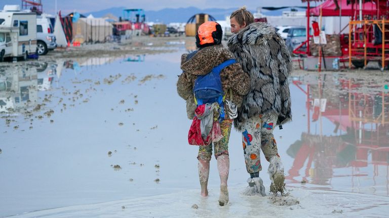 Dub Kitty and Ben Joos, of Idaho and Nevada, walk through the mud at Burning Man after a night of dancing with friends in Black Rock City, in the Nevada desert, after a rainstorm turned the site into mud September 2, 2023. Trevor Hughes/USA TODAY NETWORK via REUTERS NO RESALES. NO ARCHIVES.
