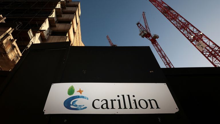 A logo is seen in front of cranes standing on a Carillion construction site in central London