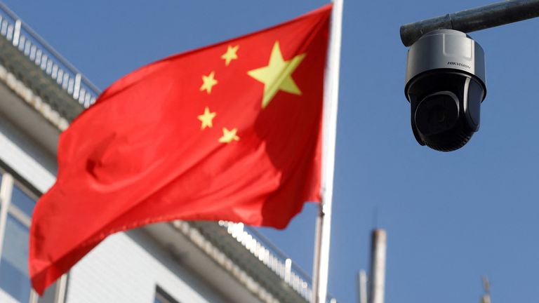 FILE PHOTO: A security surveillance camera overlooking a street is pictured next to a nearby fluttering flag of China in Beijing, China November 25, 2021. Picture taken November 25, 2021. REUTERS/Carlos Garcia Rawlins/File Photo