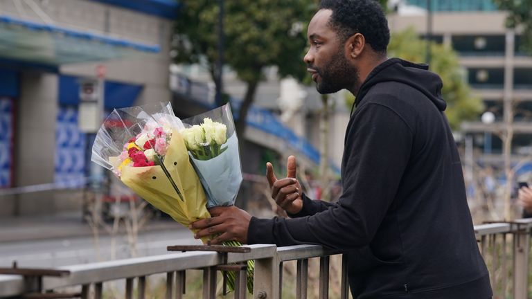 A wellwisher arrives with flowers at the scene