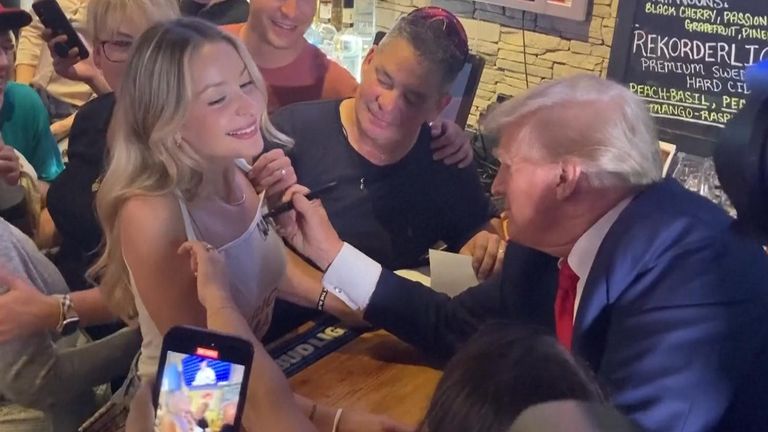 Donald Trump signs a woman&#39;s tank top in a restaurant in Iowa