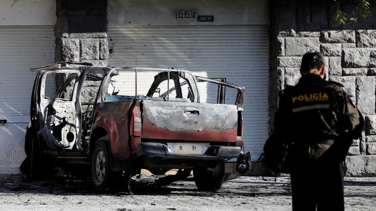 A police officer stands near the remains of a car, that according to authorities was loaded with two gas tanks and later exploded when suspects set it on fire, seemingly targeting Ecuador&#39;s prison agency SNAI, in Quito, Ecuador August 31, 2023. REUTERS/Karen Toro
