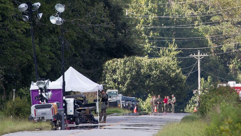 Local law enforcement and military officers stand at  checkpoints along Old Georgetown Road, Tuesday, Sept. 19, 2023,  in Williamsburg County, S.C., about 60 miles (96 km) northeast of Joint Base Charleston  where a recovery operation for an F-35B Lightning II crash landed over the weekend. (Henry Taylor/The Post And Courier via AP)