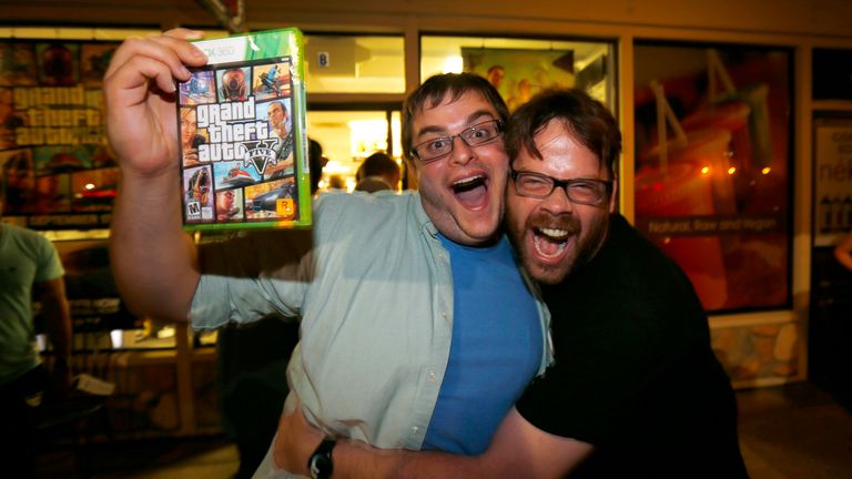 Gaming enthusiast Casey Riffel holds up his copy of the latest release of "Grand Theft Auto Five" as he gets a hug from animator Michael Petterson after midnight at a Game Stop gaming store in Encinitas, California September 17, 2013. Petterson is a game developer who helped with animation on the game and was thrilled to see a large crowd at midnight to support his work. REUTERS/Mike Blake (UNITED STATES - Tags: ENTERTAINMENT SCIENCE TECHNOLOGY BUSINESS TPX IMAGES OF THE DAY)