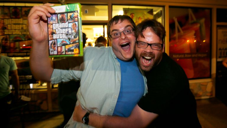 Gaming enthusiast Casey Riffel holds up his copy of the latest release of "Grand Theft Auto Five" as he gets a hug from animator Michael Petterson after midnight at a Game Stop gaming store in Encinitas, California September 17, 2013. Petterson is a game developer who helped with animation on the game and was thrilled to see a large crowd at midnight to support his work. REUTERS/Mike Blake (UNITED STATES - Tags: ENTERTAINMENT SCIENCE TECHNOLOGY BUSINESS TPX IMAGES OF THE DAY)