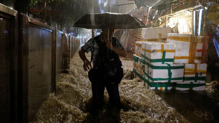 A man walks past a flooded area during heavy rain in Hong Kong