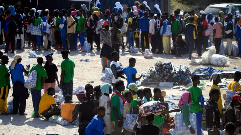 FILE - Migrants stand in the Lampedusa&#39;s migrant reception center, Sicily, Thursday, Sept. 14, 2023. Thousands of migrants and refugees have landed on the Italian island of Lampedusa this week after crossing the Mediterranean Sea on small unseaworthy boats from Tunisia, overwhelming local authorities and aid organizations. (AP Photo/Valeria Ferraro, File)