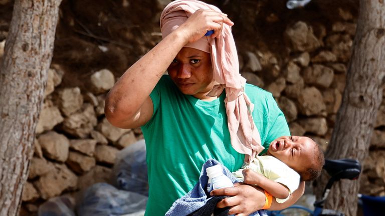 A migrant on Lampedusa holds a new born baby